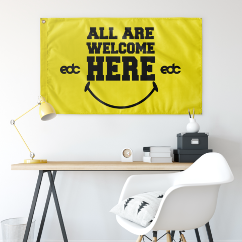 Yellow EDC smiley flag hung above a desk setup in a bright home office