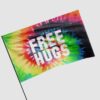 Angled close-up of rainbow tie dye rave flag on a pole showing FREE HUGS lettering