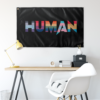 Black HUMAN flag hung above a desk with yellow lamp and white chair