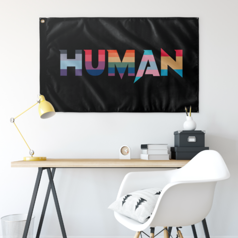 Black HUMAN flag hung above a desk with yellow lamp and white chair