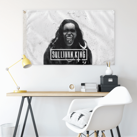 Sullivan King grayscale photo flag above a desk with distressed splatter texture and bird emblem