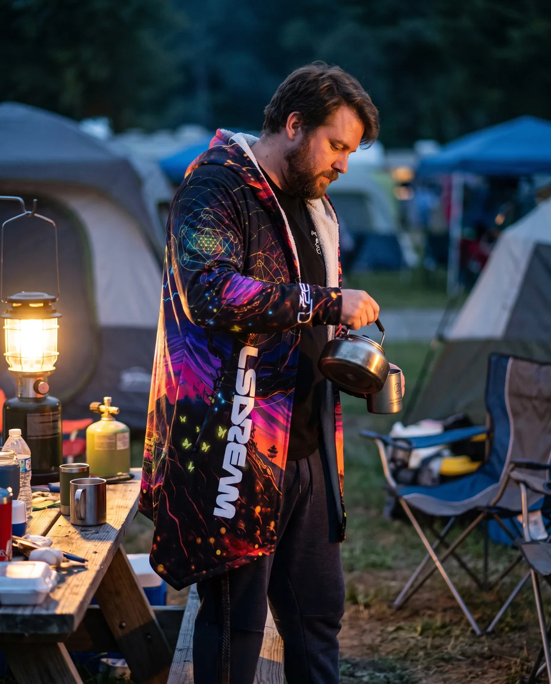 Man wearing a hooded rave cloak over a tee at a festival campsite