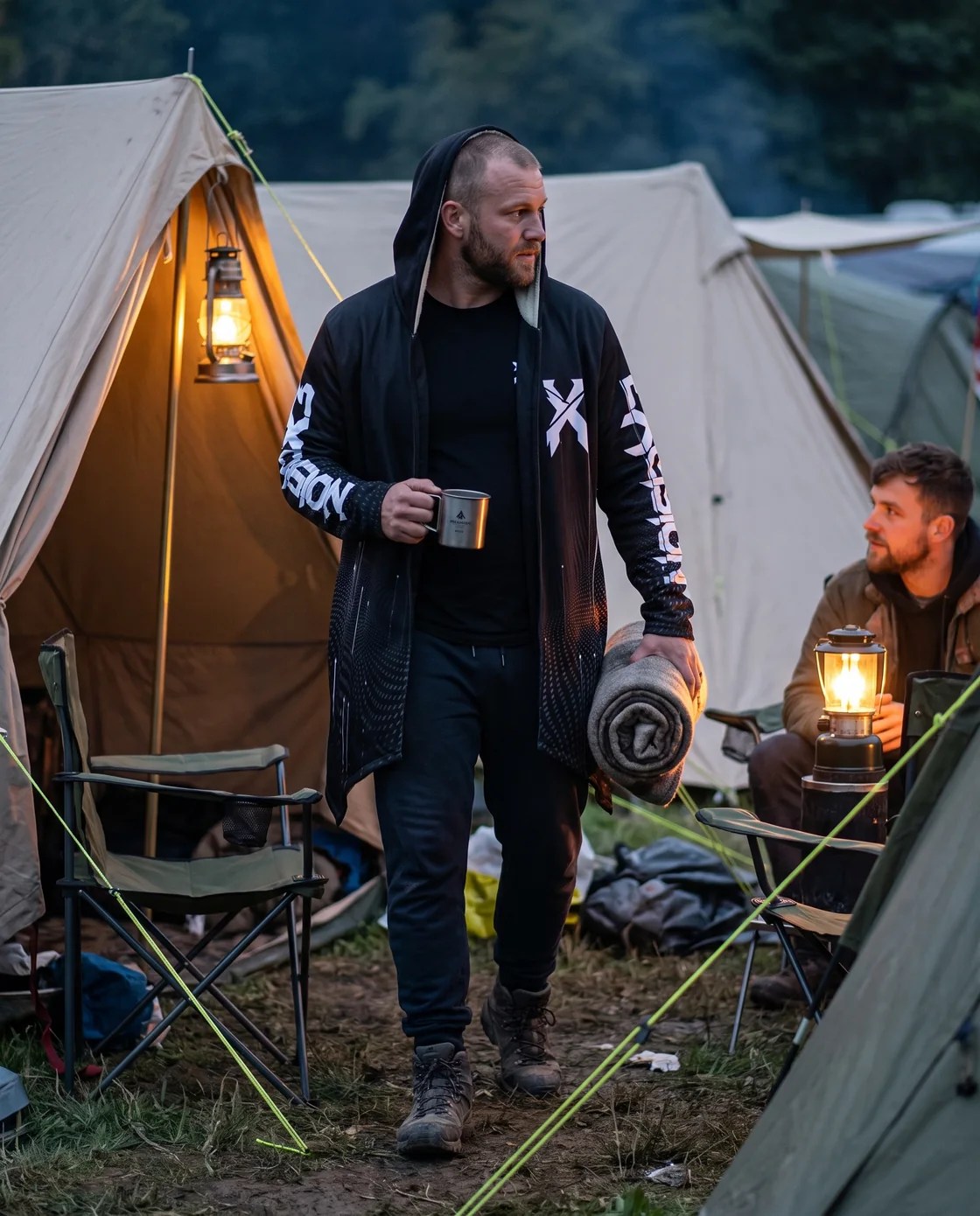 Man wearing a hooded rave cloak over a tee at a festival campsite