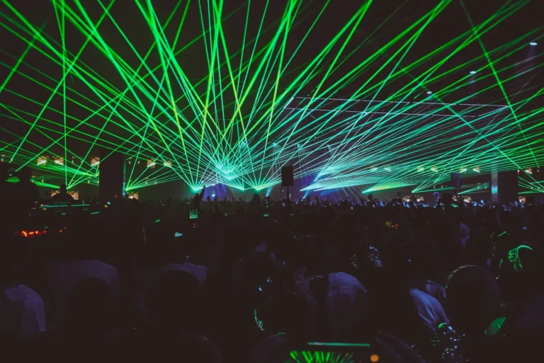 Crowd dancing beneath lasers at a nighttime rave