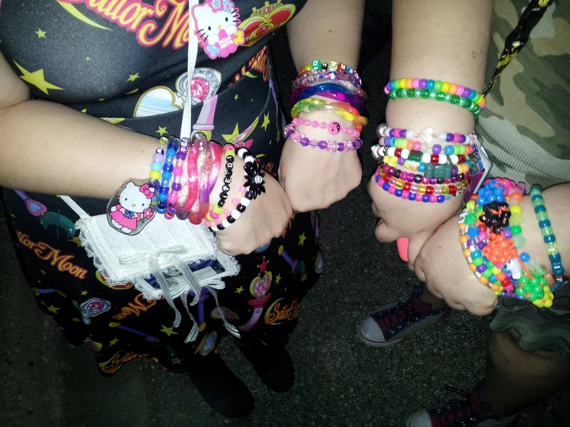 Friends trading kandi bracelets with a PLUR handshake