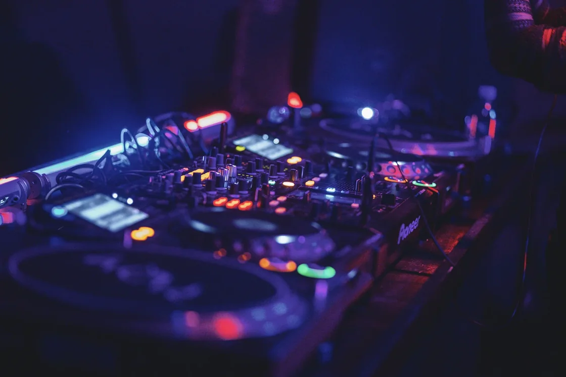 DJ mixer and CDJs in a dark booth under purple light