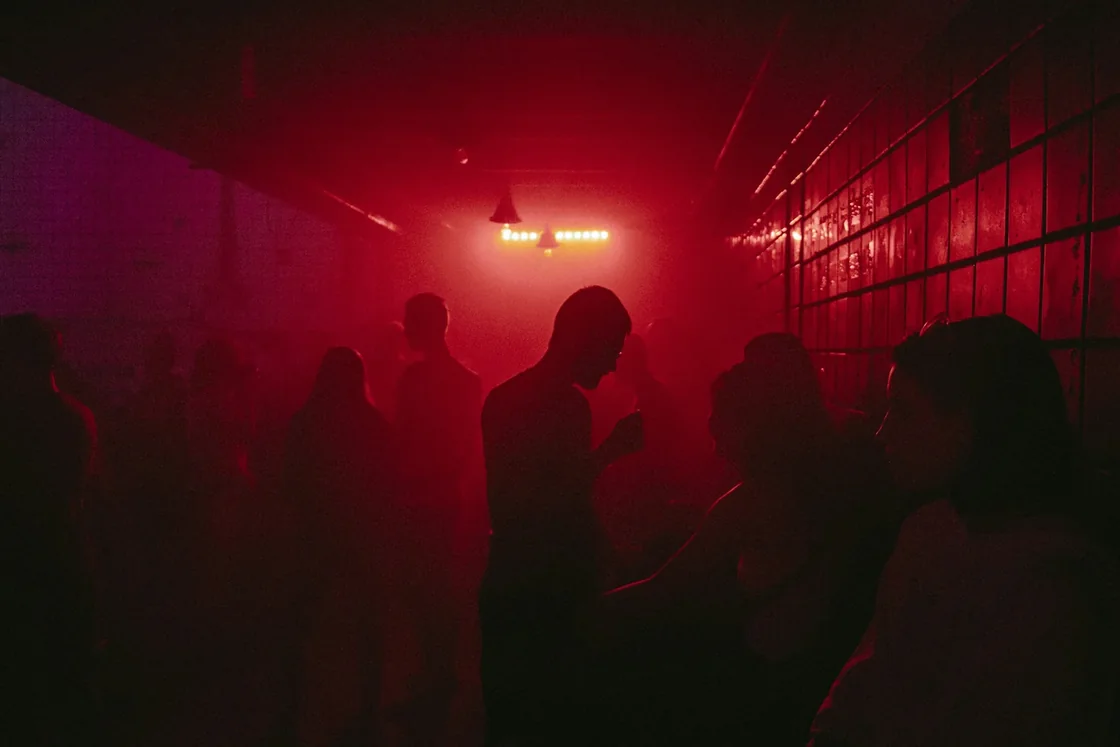 Small crowd dancing under red light at a club night