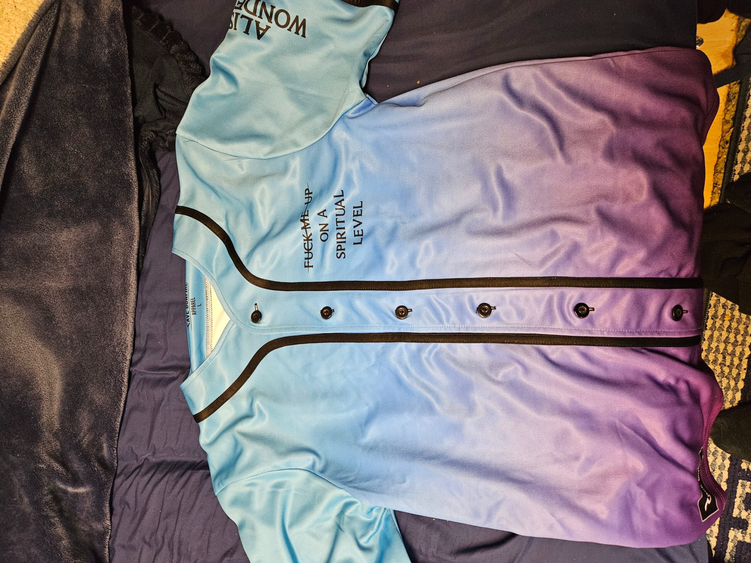A Marud custom Baseball Jersey in blue and purple on a bed.