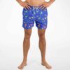 Model wearing royal blue rave swim trunks with colorful dinosaur silhouette pattern