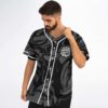 Model wearing black-gray abstract swirl jersey with white piping and bubble-letter chest text, front view