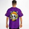 Model wearing purple jersey with skull emblem, yellow hat, crossed bones, back view