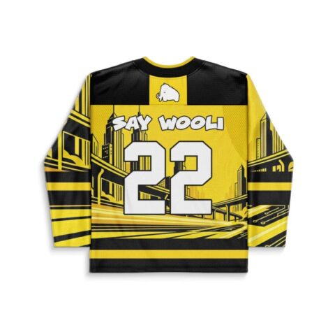 Cartoon-style yellow-and-black cityscape jersey back with “SAY WOOLI,” white mammoth icon, and number 22