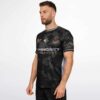 Profile view of model wearing black camo rave soccer jersey with colorful side detail