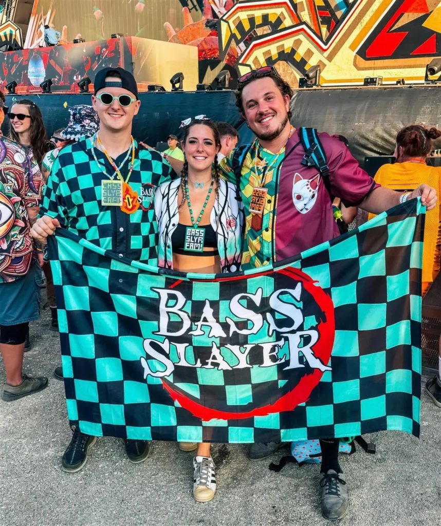 Rave crew in custom checkered jerseys holding their Bass Slayer flag at a festival
