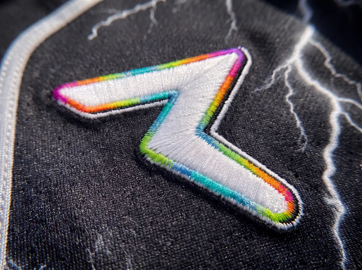 Close-up of a raised embroidered crest on a printed rave jersey, with the thread texture visible