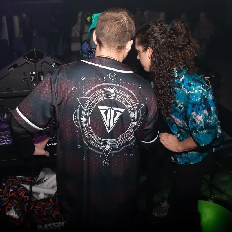 DJ seen from behind wearing a black custom jersey with a geometric logo