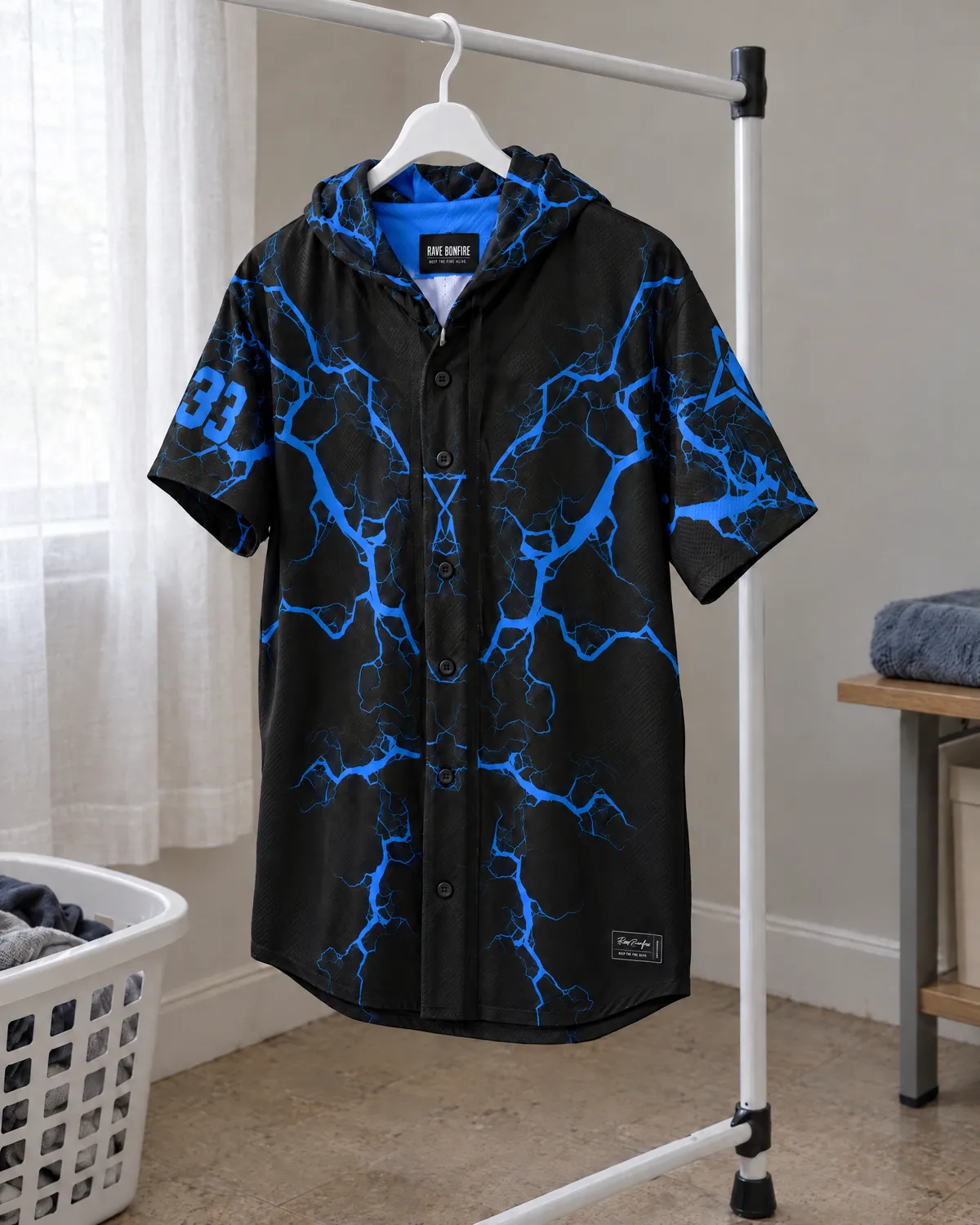 Black blue-lightning hooded baseball jersey air-drying indoors on a plastic hanger.